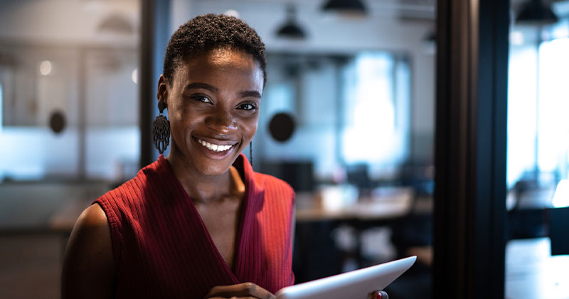 Healthcare administration student holding tablet and smiling